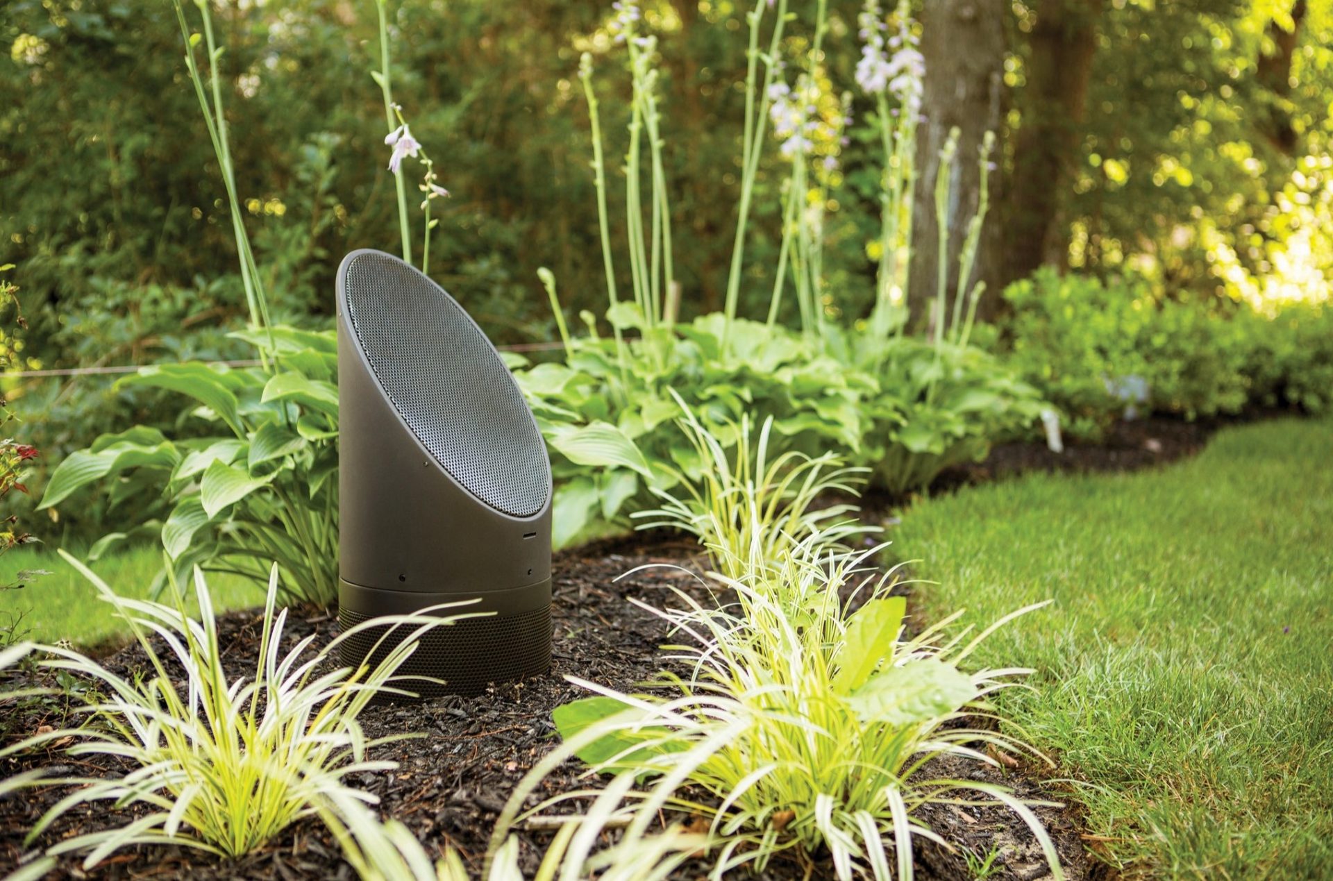 An example of an outdoor speaker installed in a flower bed.