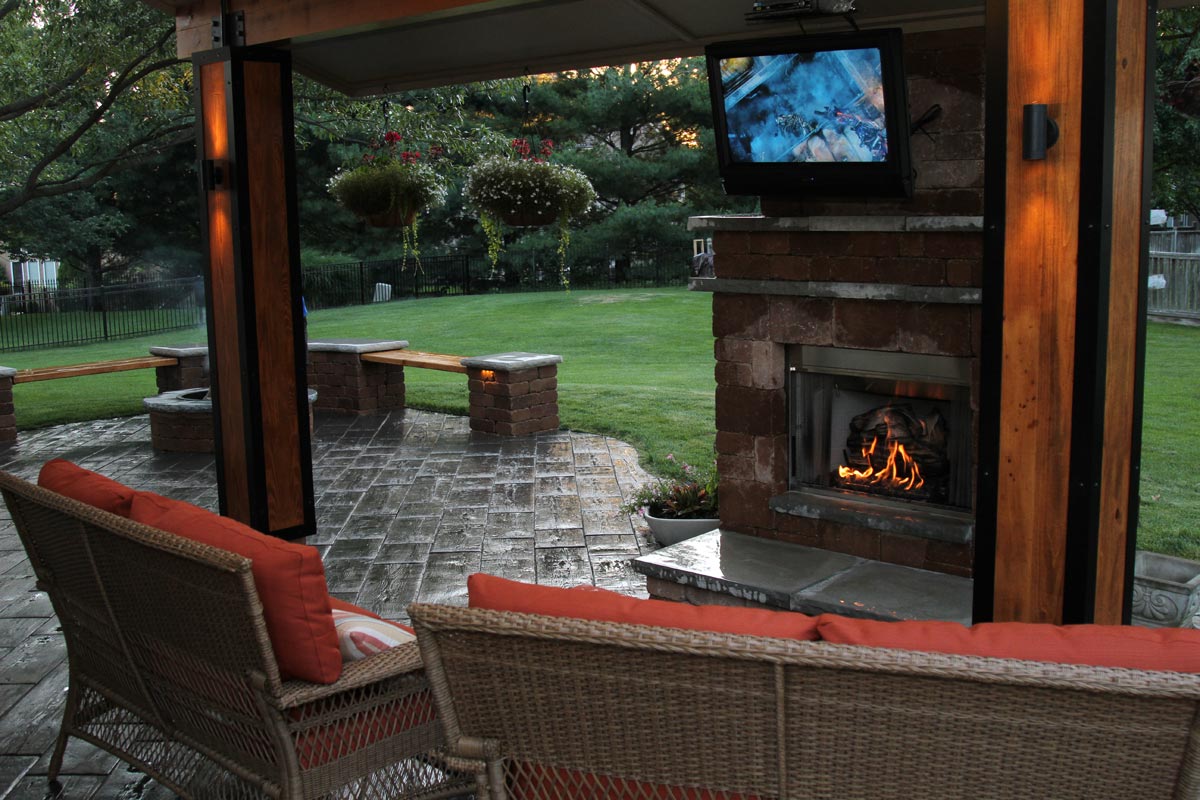 A fireplace with a fire in it in an outdoor living area.