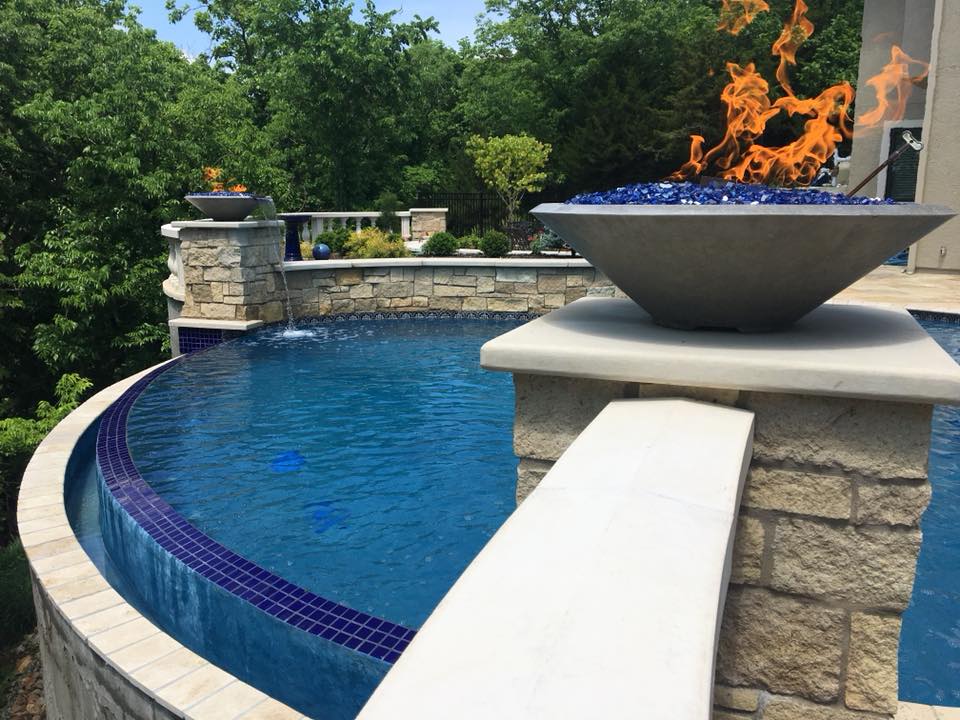 A lit fire bowl over an infinity pool.