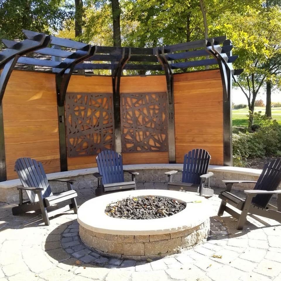 A wall ouitdoors with chairs and a firepit sitting in front of the wall.