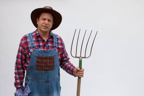 Farmer in bib overalls and holding a pitchfork