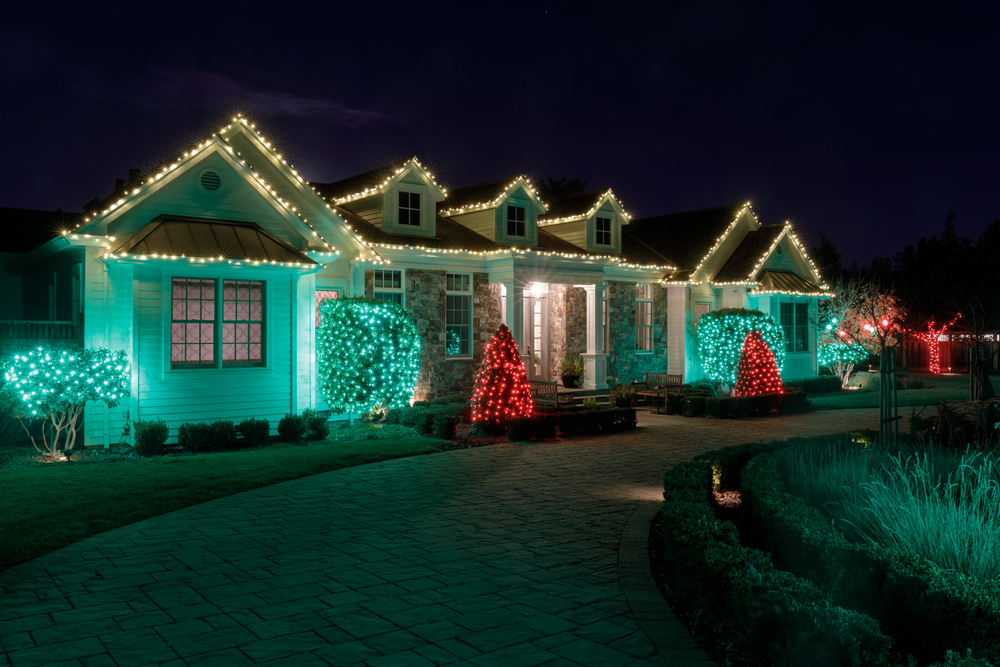A house with green, red, and white Christmas lights on it at night.