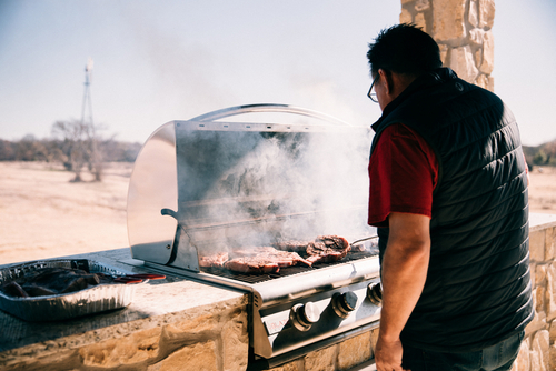 A man cooking food on a grill in a stone wall.