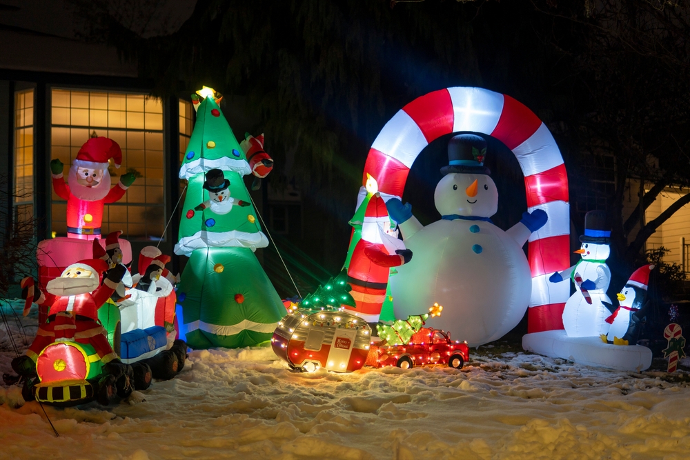 Inflatable holiday winter figures in a front yard at night.