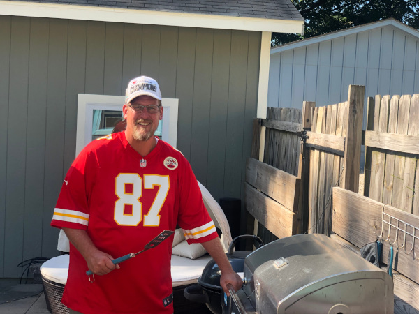 Picture of Andy Wright standing by a grill ready to cook food.